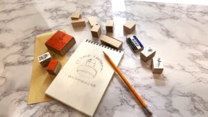 スタンプのデザインデータと完成したオリジナルスタンプが並ぶ作業机の様子