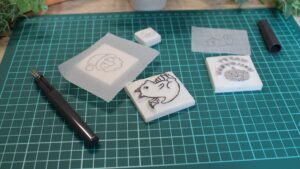 100均の道具で作れる消しゴムはんこ制作キットと完成品が机に並んでいる様子