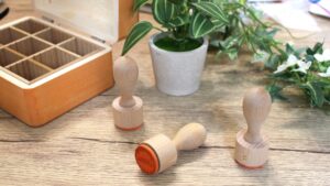 木製持ち手付きのラバースタンプが並ぶ温かみある作業机の様子。