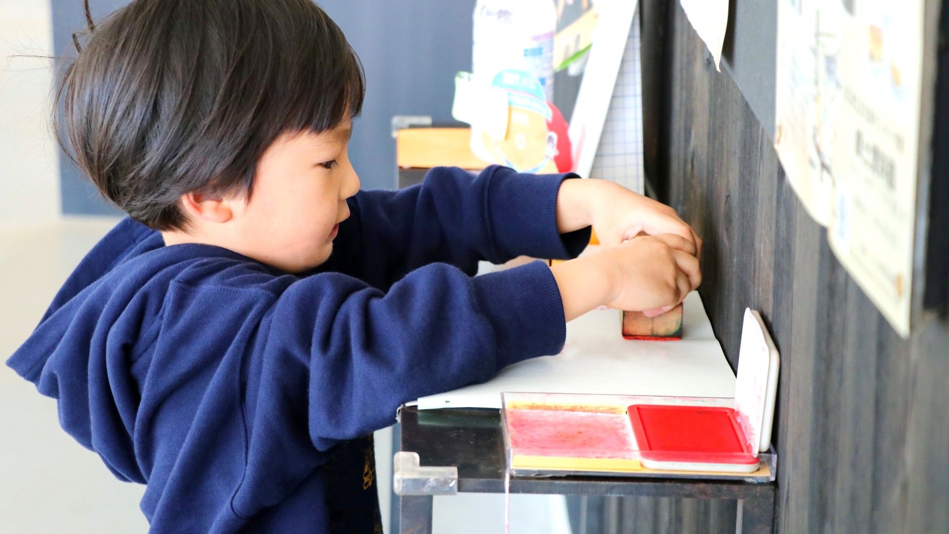 小さい子が机の上ではんこを押して楽しんでいるシーン
