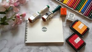 机の上でオリジナルスタンプを押してアートセラピーを楽しむ人の手元の様子。