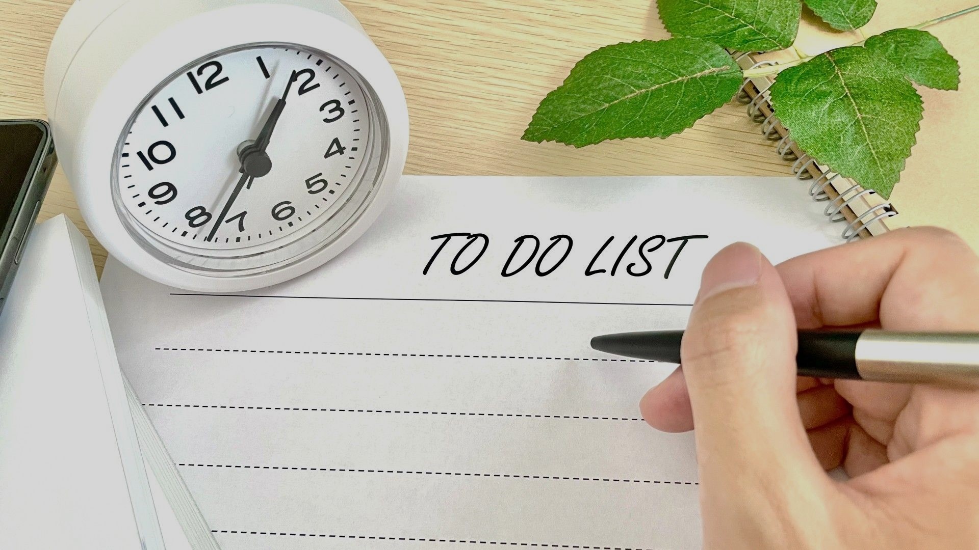 手帳、文具などが並んだ机の上で作業するスタンプ作家のデスク風景。