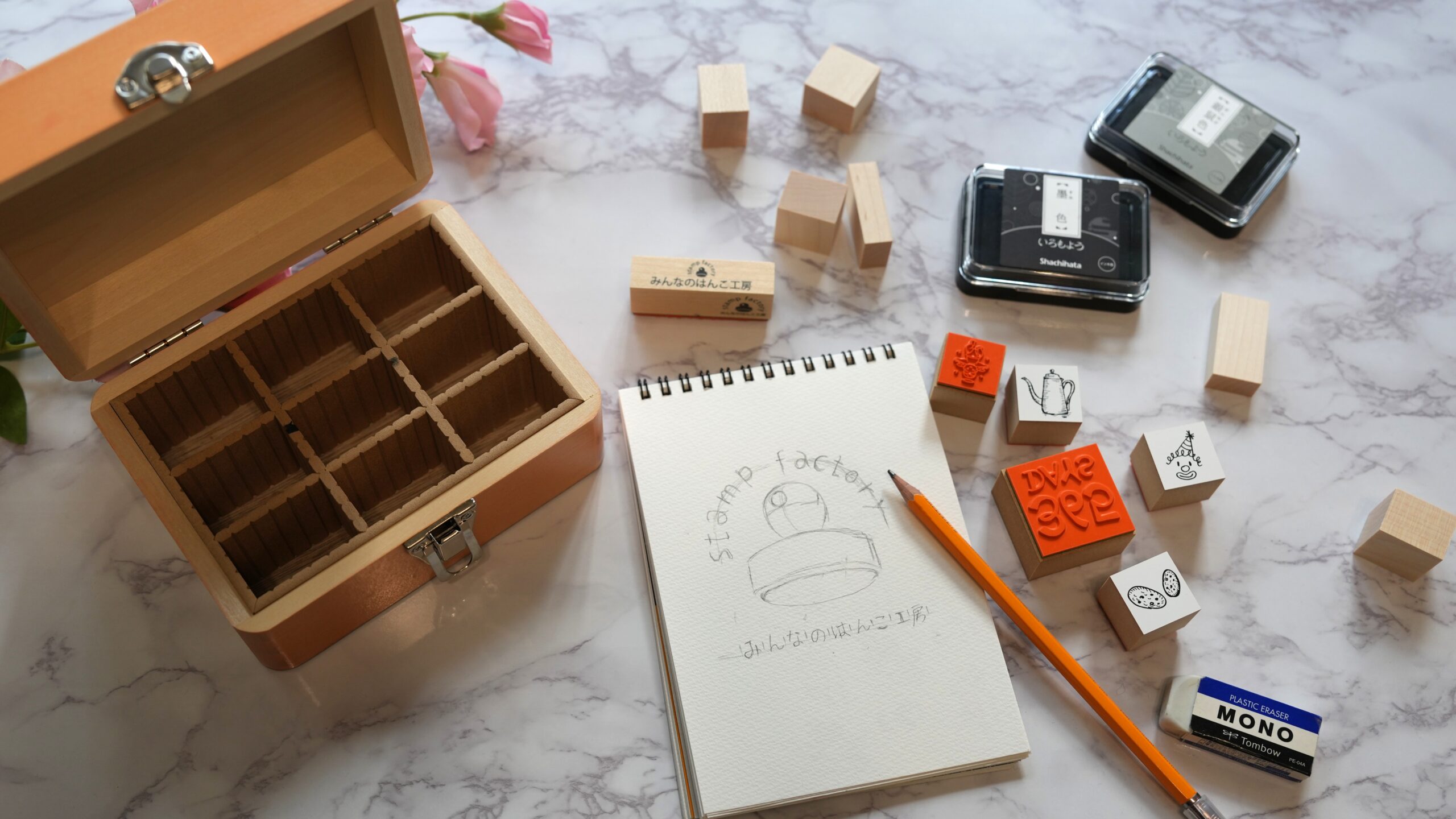 オリジナルスタンプと手描きイラスト、インクパッドが並んだ明るい作業風景のイメージ。