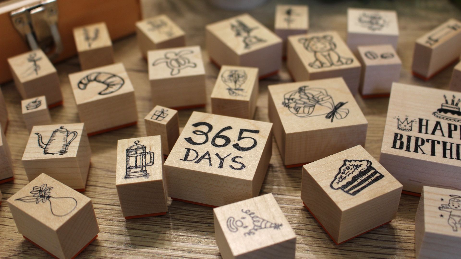 木のデスクの上に並ぶ人気デザインのラバースタンプ。動物、英字、植物など多様なモチーフが見える。