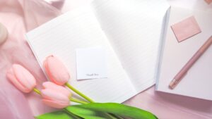 かわいいフォントが押印された印影のメッセージカードと手帳や文具が一緒に撮影された明るい雰囲気の写真。