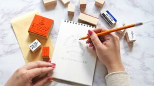 ひらがなの作家名ロゴと、手描き風のスタンプ作品が並んだ、優しい雰囲気のイラスト。