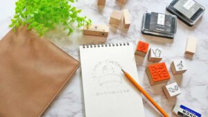 自宅で道具を広げ、はんこ作りの副業に取り組む様子が分かる作業風景。