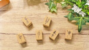 手帳の上に花や動物のオリジナルスタンプが並び、優しい光に包まれた癒しを感じる文具コーナーのイメージ。