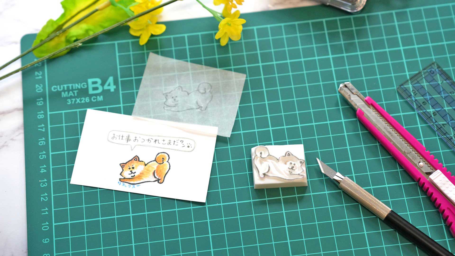 作業机の上に並ぶはんこ用イラスト素材や彫刻道具、完成したスタンプ作品の写真